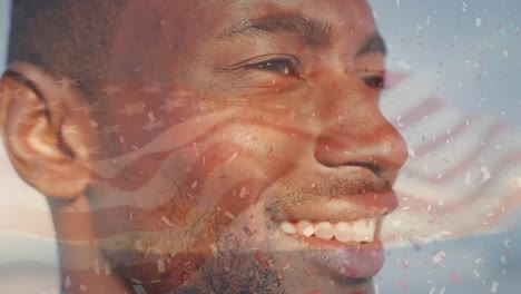 animation of flag of united states of america and confetti over african american man on beach