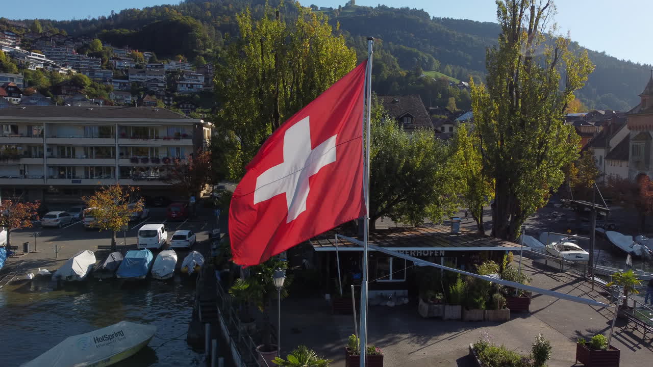 En fantastisk flygbild med inflygning mot Schweiz flagga, fotograferad i Oberhofens kommun i Schweiz, en solig dag.
