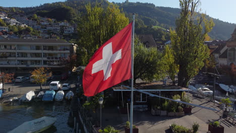 fantastic aerial shot in approach to the flag of switzerland, shot made in the municipality of oberhofen in switzerland, on a sunny day