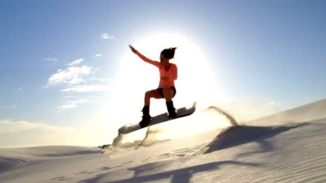 Woman-performing-a-jump-while-sand-boarding-4k