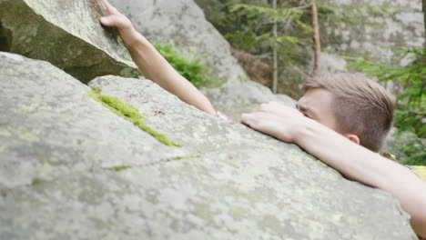 a heavy climb up the mountain through the rocks a young concentrated man scrambles up the stonesl 4k