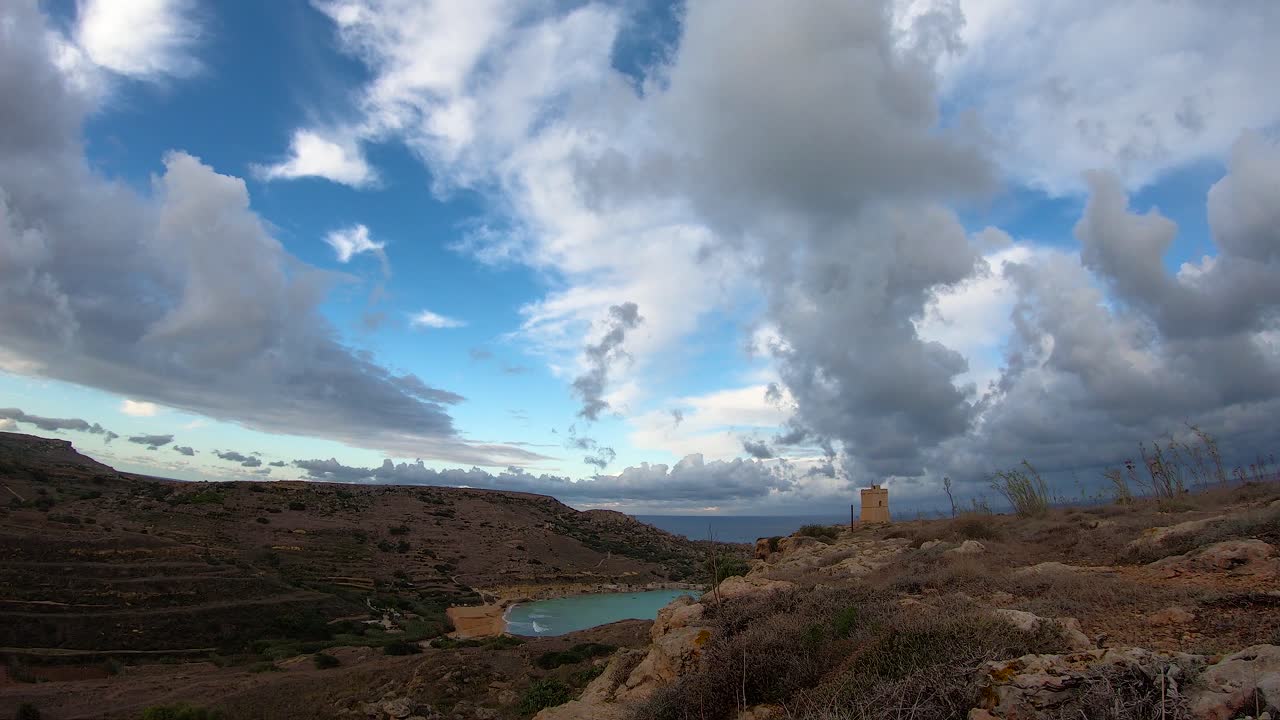 lapso de tiempo épico de las nubes a la deriva sobre el cielo azul brillante sobre la playa de ghajn tuffieha malta, bahía de gnejna