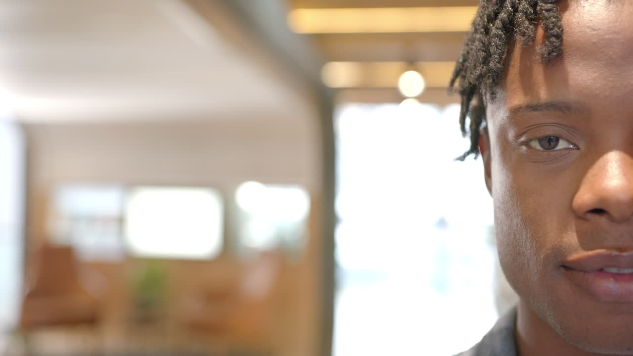 Smiling man with dreadlocks in modern office, focusing on work, copy space