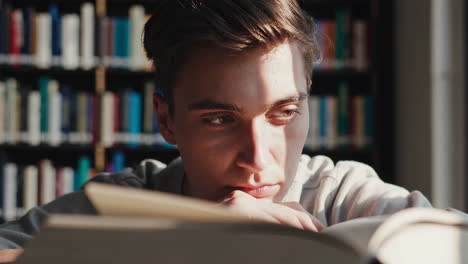 young man studying and reading a book in a library
