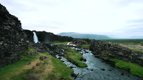 revealing oxararfoss waterfall at thingvellir national park in a rift valley, iceland, cinematic drone shot