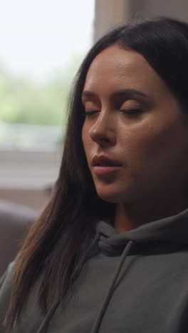 vertical video of anxious woman sitting indoors on chair working from home using laptop worried about cost of living crisis