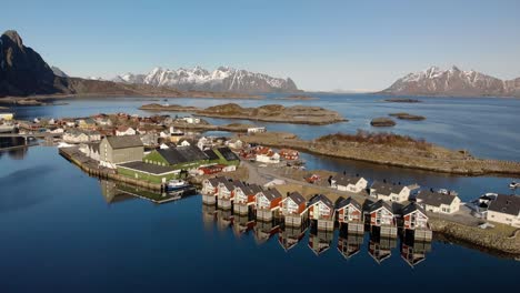 aerial drone shot of cottages in lofoten norway with big mountains in the background. surrounded by the ocean