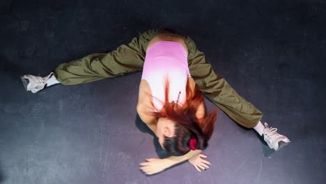 attractive young woman with sportswear stretching in splits on the floor in a dance studio, top view