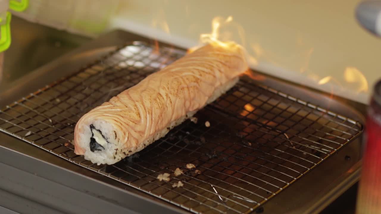soplar fuego con una antorcha en el sushi en el mercado callejero