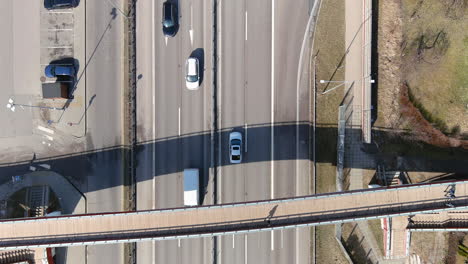 top down aerial view of highway traffic and pedestrian bridge overpass on sunny autumn day, high angle drone shot