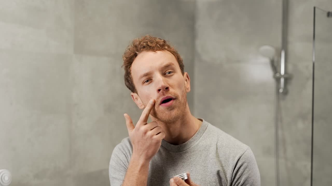 곱슬 잘생긴 남자는 얼굴에 크림을 적용