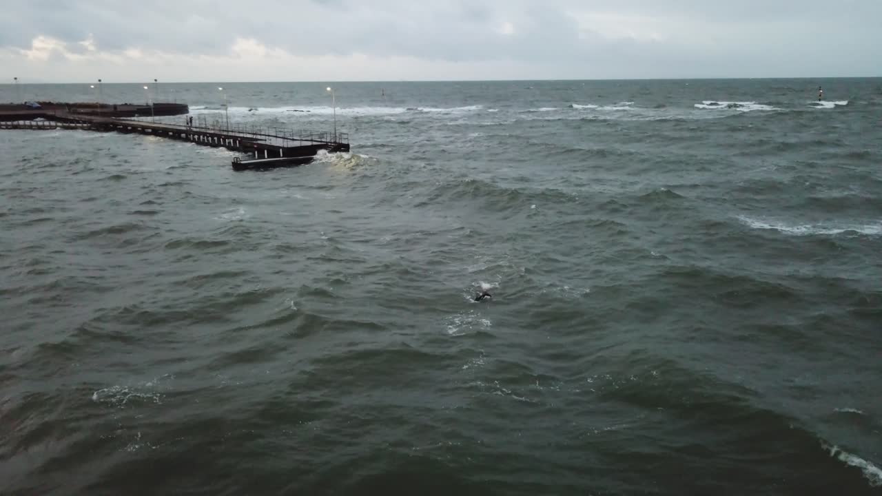잠수복에서 수영하는 바다 멜버른 물결 모양의 바람이 흐린 사람 위에 무인 항공기 공중