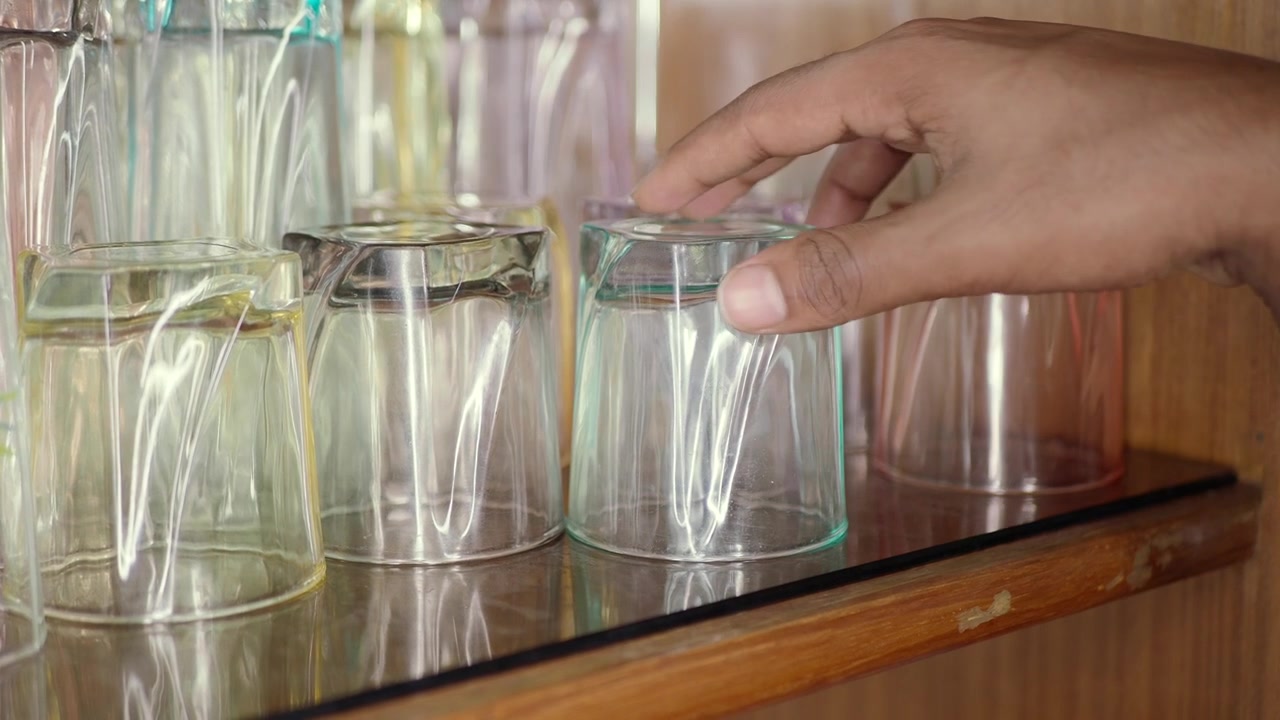 Eine Hand nimmt ein Glas aus einem Regal