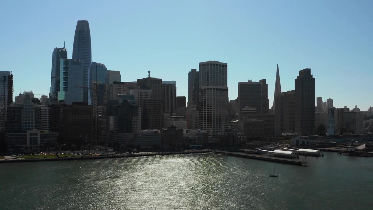 Ripresa aerea con drone che avanza verso lo spettacolare skyline del centro di San Francisco e il Ferry Building sopra il lungomare scintillante - (UHD 4K)