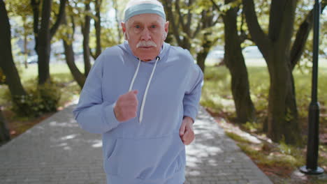 senior athletic man grandfather running jogging in sunny park during morning workout cardio outdoors