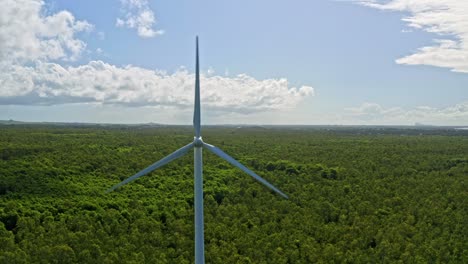 aerial dolly out reveals wind turbines in lush landscape, blue sky with clouds