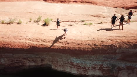 drone shot of cliff jumper doing trick in lake powell utah