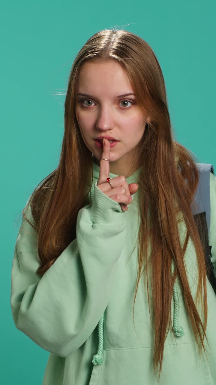 Vertical video Girl placing finger on lips, doing quiet sign gesture