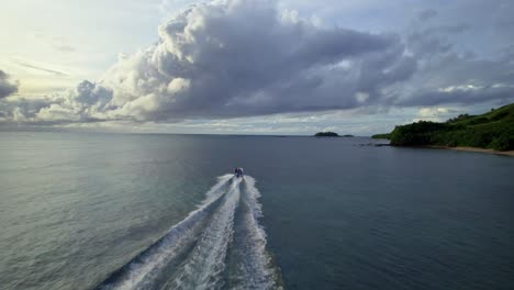 boat cruising towards cloudy horizon along the coast, yasawa islands, fiji