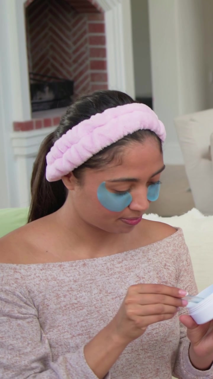 Vertical video: Smiling woman with pink headband sharing jar after friend passing spatula on couch