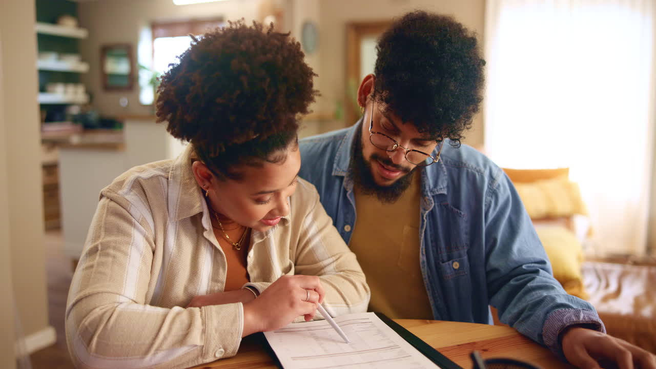 una pareja sentada en una mesa revisando el papeleo