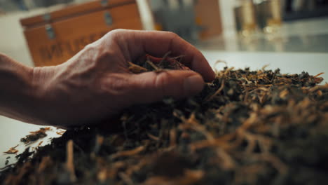 Close-up-shot-of-a-male-hand-picking-up-aromatic-dried-spice-herbs-from-a-white-table