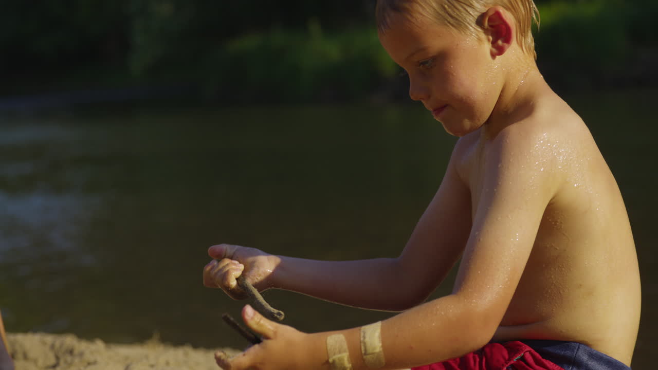 어린 아이 가 호수 에서 수영 하는 동안 모래 를 가지고 놀고 있다 - 근접