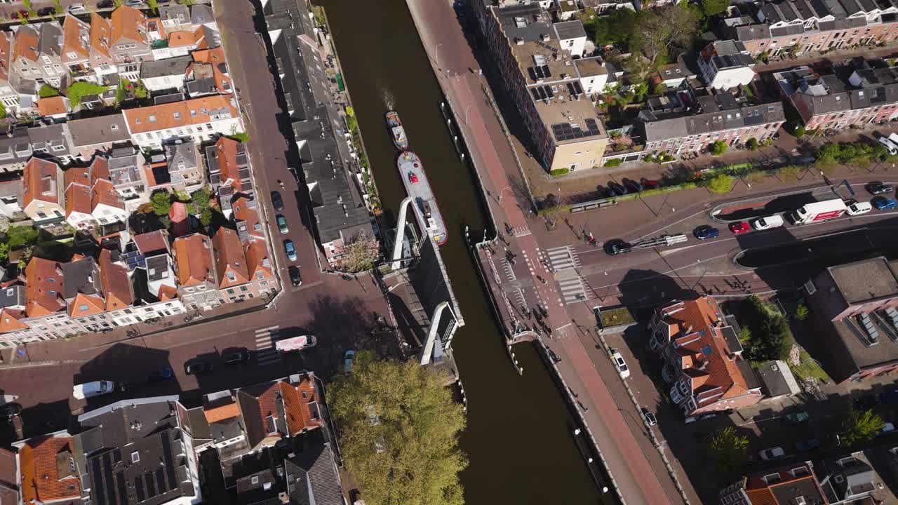 Overhead view of a canal in Delft with a raised drawbridge, boats navigating below, and vehicles waiting—showcasing Dutch infrastructure in action.