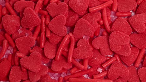 red heart-shaped candies and sprinkles cascade in a vibrant, close-up shot with consistent lighting and dynamic movement