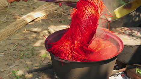 teñir pajitas de color rojo antes de tejerlas en alfombras o alfombras