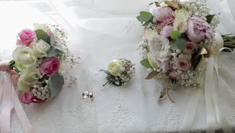 beautiful wedding bouquets lie with wedding rings near window on white curtains