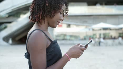 smiling african american curly woman using phone