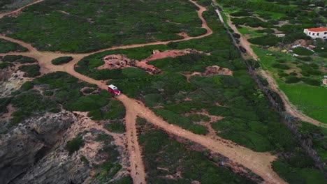 Vista-De-Pájaro-Del-Fundador-De-Un-Vehículo-4x4-Rojo-Conduciendo-Por-La-Costa-En-Un-Camino-De-Tierra