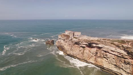vuelo aéreo hacia la fortaleza del faro en el acantilado, colores idílicos del océano - nazar?