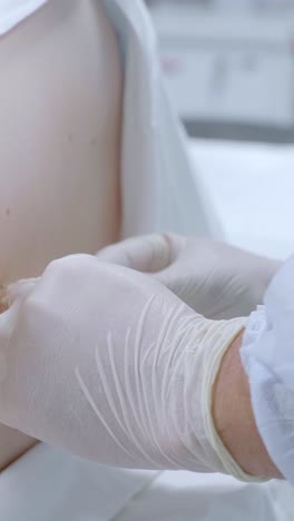 medical professional performing a procedure with a syringe on a patient's lower back in a clinical setting