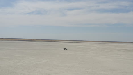 4x4 car driving on vast makgadikgadi salt pan at daytime near kubu island in botswana, south africa