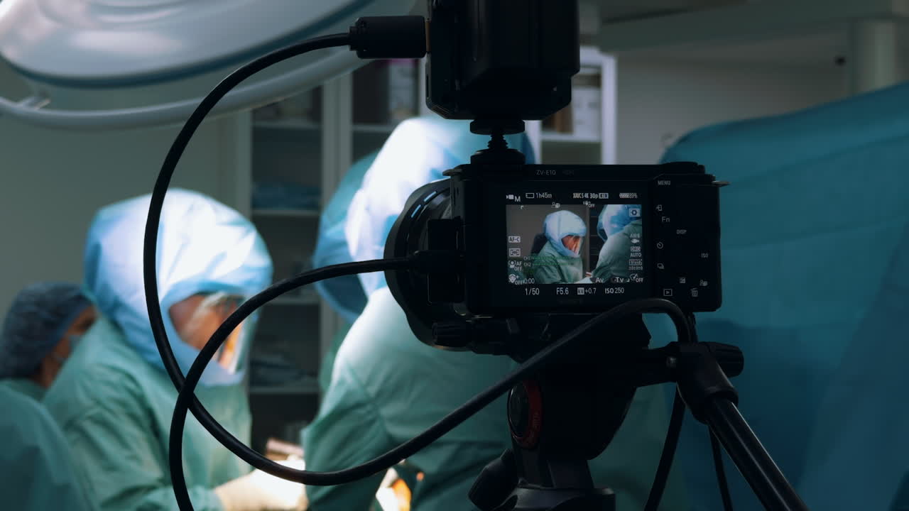 Kyiv, Ukraine, 2 August 2025: Close-up on a camera screen displaying live feed of surgeons in the operating room. A vertical angle showing the recording equipment capturing the medical team's procedure in the background