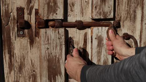 using an old metal opening mechanism to open a wooden door, close-up shot