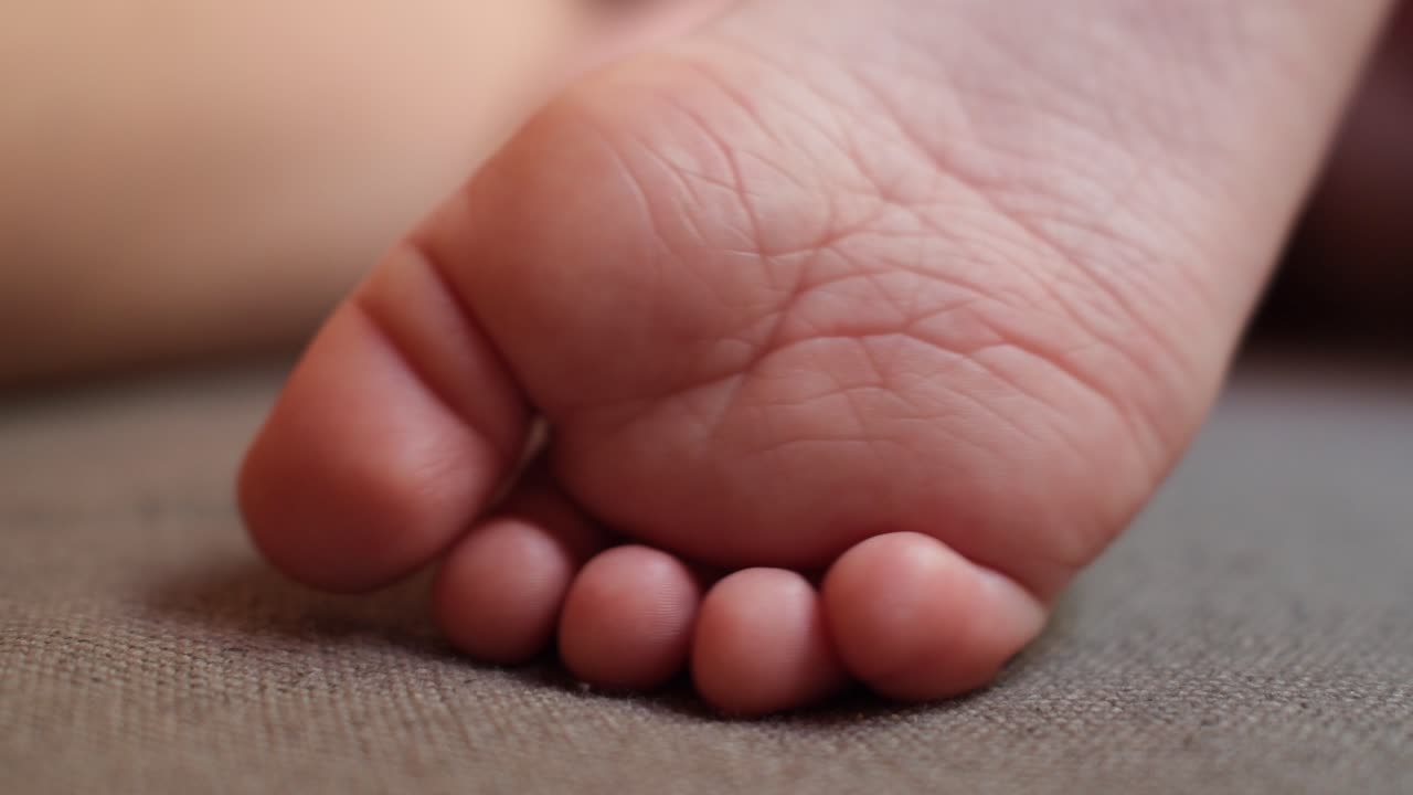 Close-up of baby toes moving softly, capturing natural infant reflexes, gentle motion, and peaceful care moments in a warm home environment