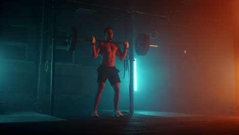 Muscular-fitness-man-doing-push-a-barbell-over-his-head-in-modern-fitness-center.-Functional-training.-Snatch-exercise.-Slow-motion-color-LED-light-saturated-bright-colors
