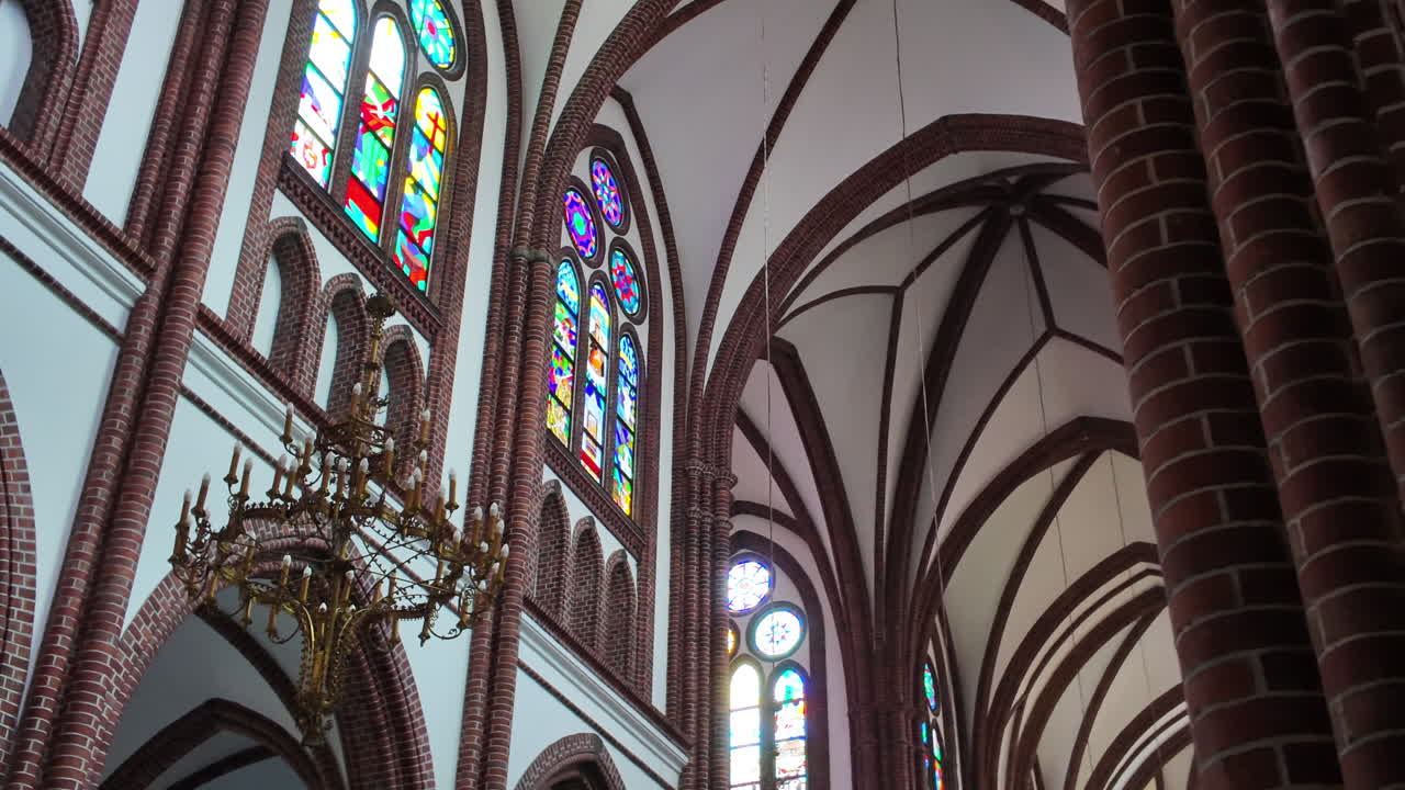 Interior view of a church with stained glass windows and chandelier in Warsaw