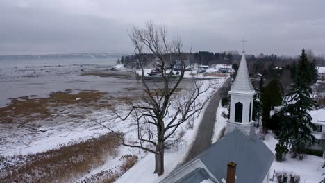 drone flying near a church on the edge of the saint-lawrence river in wintertime