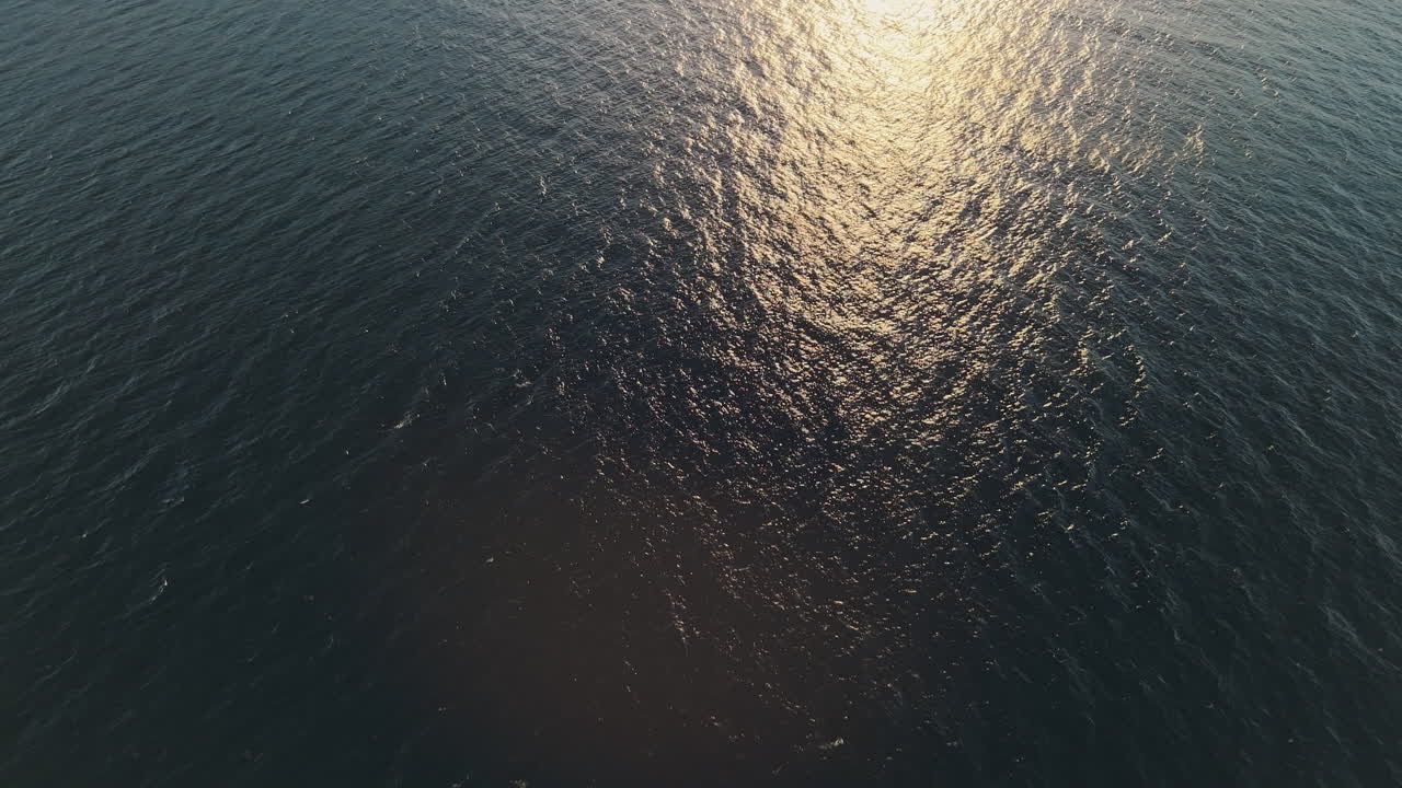 Aerial View of Golden Sunset Reflection on Ocean with Coastal City and Mountains