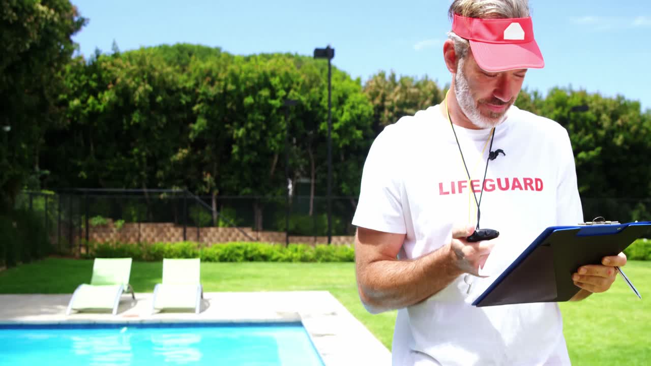 Lifeguard holding clipboard and looking at stop watch