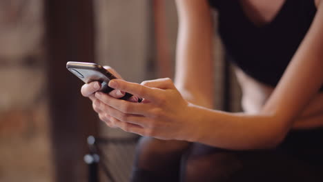 Beautiful-Female-Athlete-Text-Messaging-Through-Mobile-Phone-During-Break-At-Health-Studio