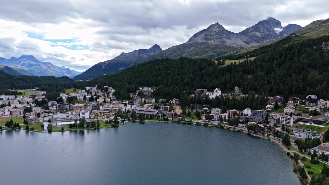 Scenic aerial of Saint Moritz with mountains and lake under cloudy sky