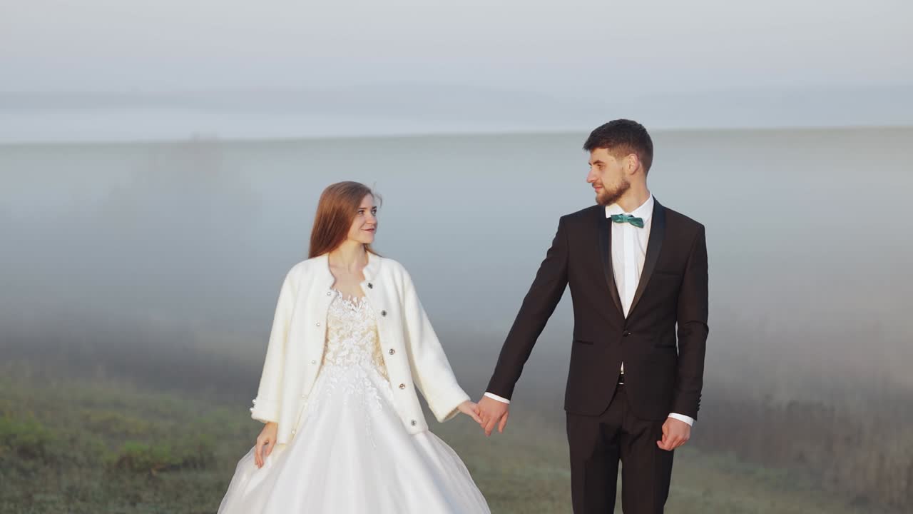 Newlyweds. Caucasian groom with bride on the morning field. Fog. Wedding couple