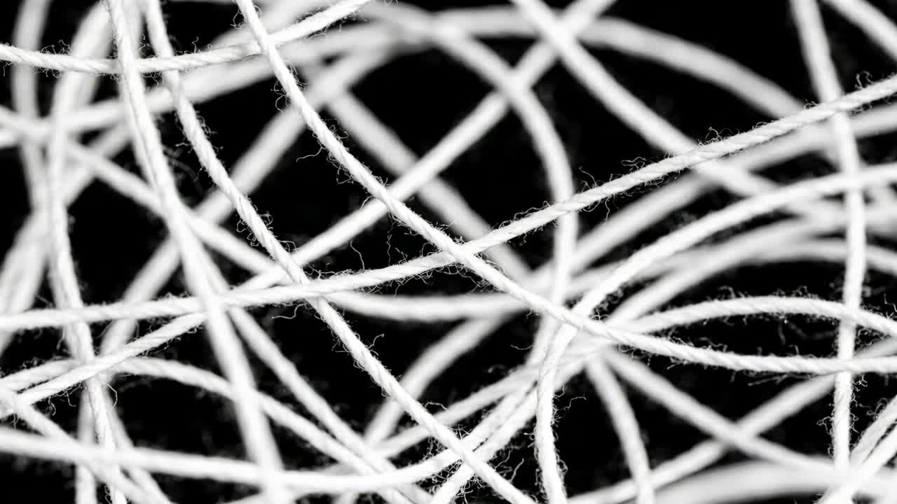 Recording tangled white thread mass shifting and sliding in macro close-up, showing frayed fibers