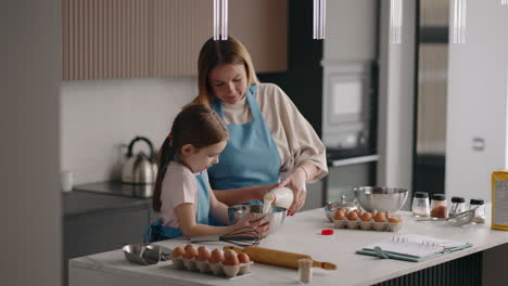 family in kitchen in sunday morning mother and little daughter are cooking omelette with eggs