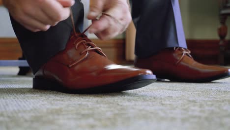 low angle closeup of a man tying his brown leather dress shoes in slow motion